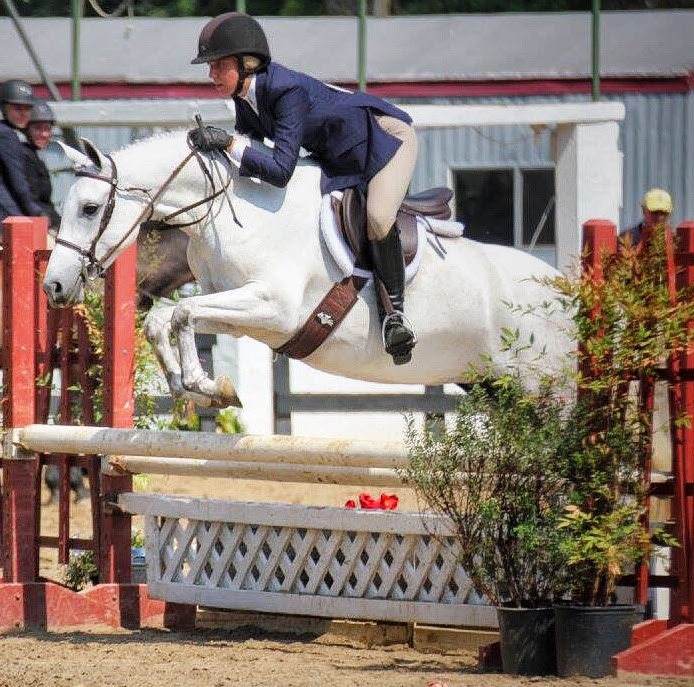 Marina Frano jumping a grey horse over an oxer at a hunter show